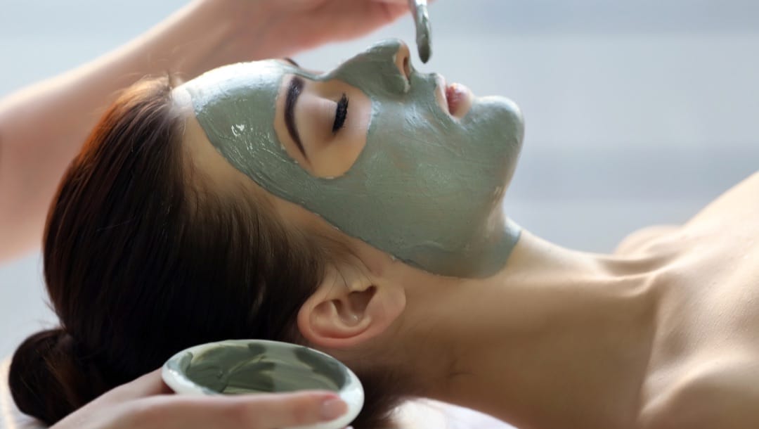 A woman has a face mask applied to her skin at a spa.