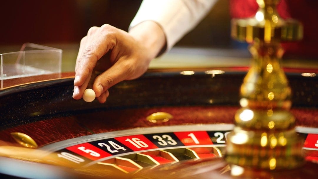 A croupier about to drop a ball into a roulette wheel.