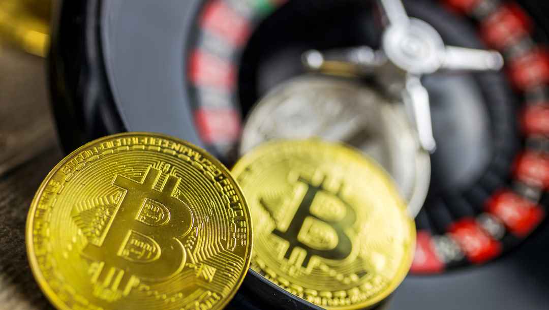 Bitcoin cryptocurrency and a roulette wheel in the background.