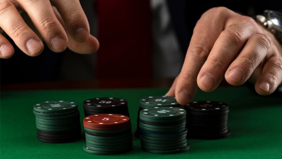 A man holding his hands above poker chips on a poker table.