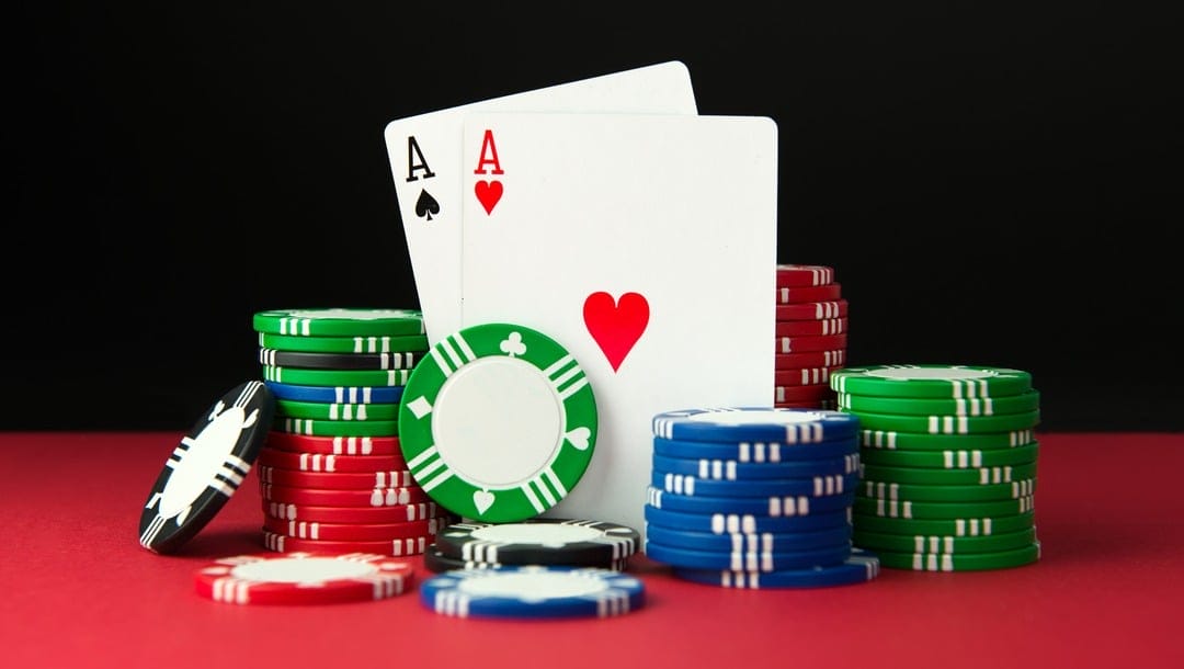 A pair of aces are propped up by stacks of poker chips.