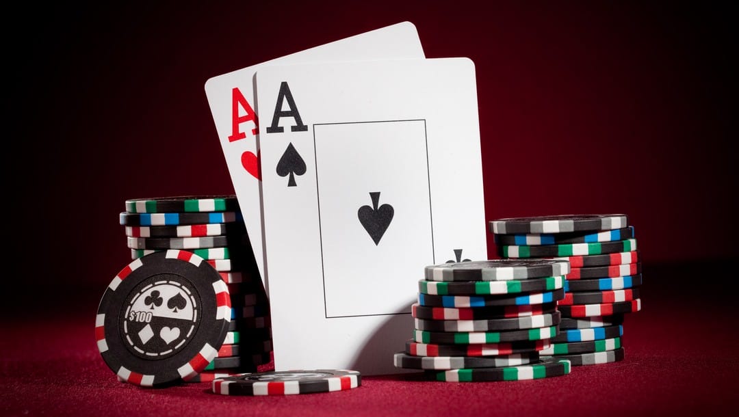A pair of aces sit between stacks of poker chips.