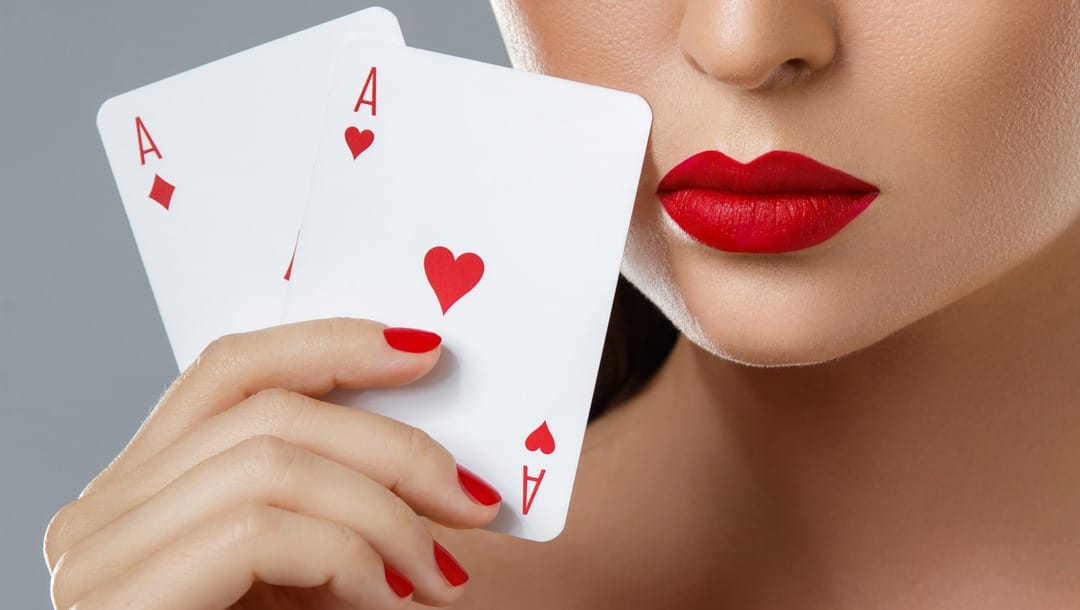 A woman reveals her hole cards, which are a pair of aces.