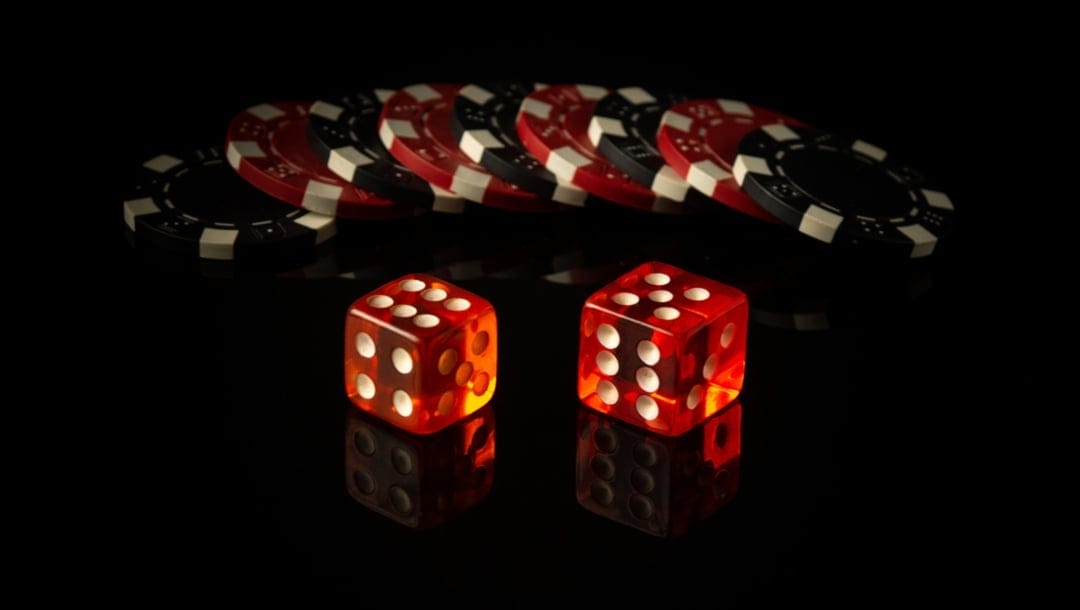 A pair of dice with casino chips behind them.