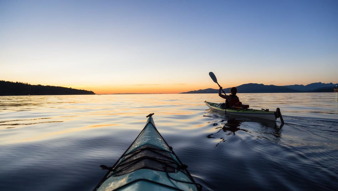 Two sea kayakers during sunrise in Jericho, Vancouver, British Columbia.
