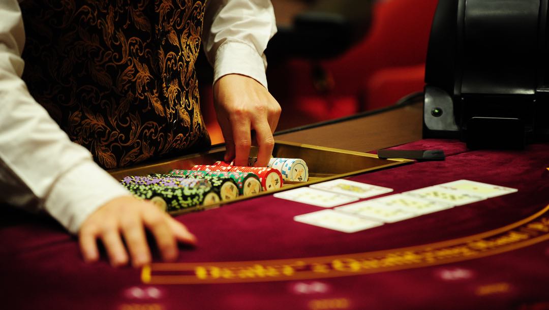A croupier taking casino chips out at a poker table.