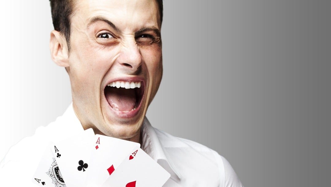 A man with a crazy expression holds four aces.