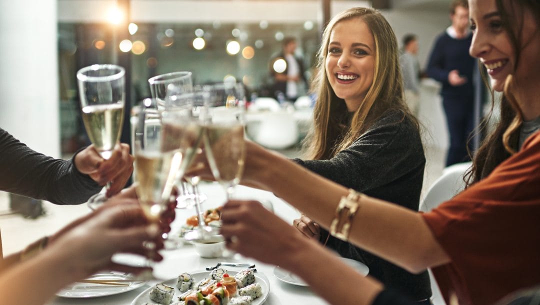 A group of friends celebrating at a restaurant with a glass of champagne.