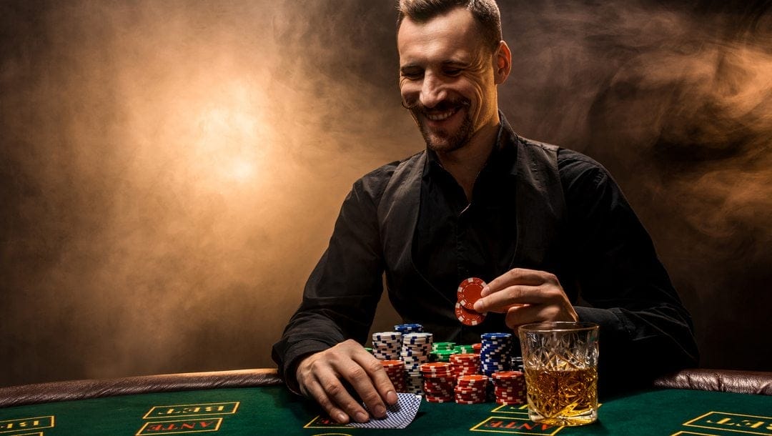 A poker player smiles as he checks his hole cards and looks to bet.