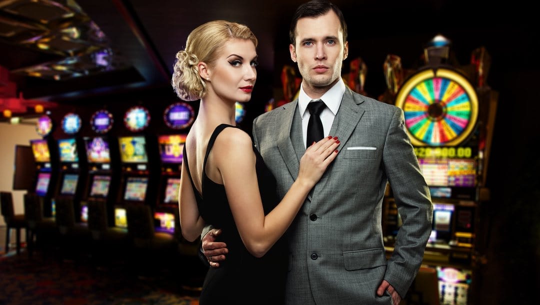 A good-looking, well-dressed couple pose together in front of casino games.