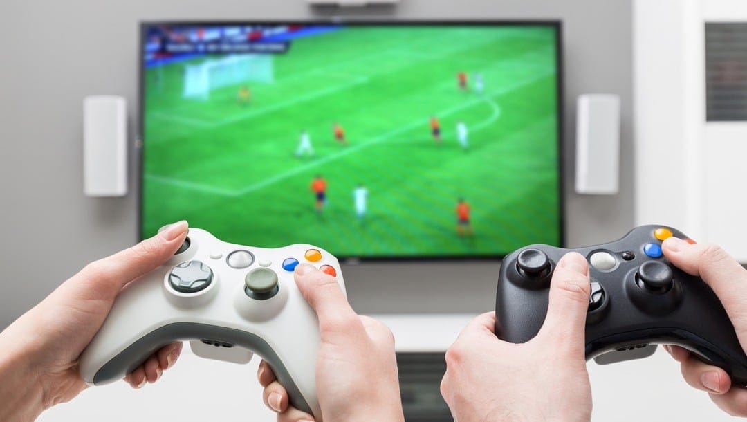 Two people play a soccer game on a video game console.