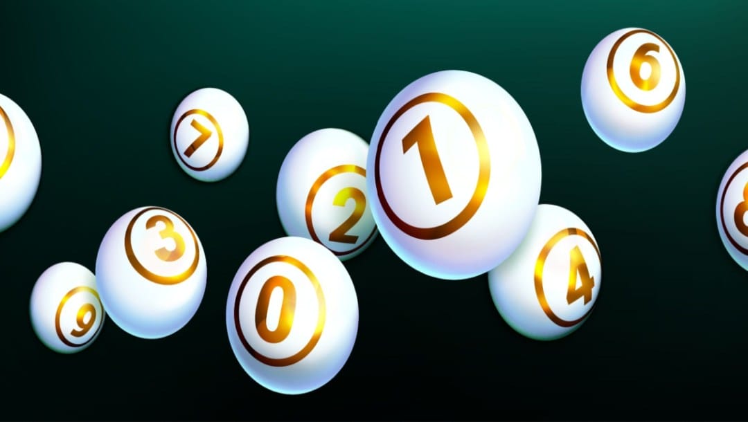 White and gold lottery balls against a black and dark green background.