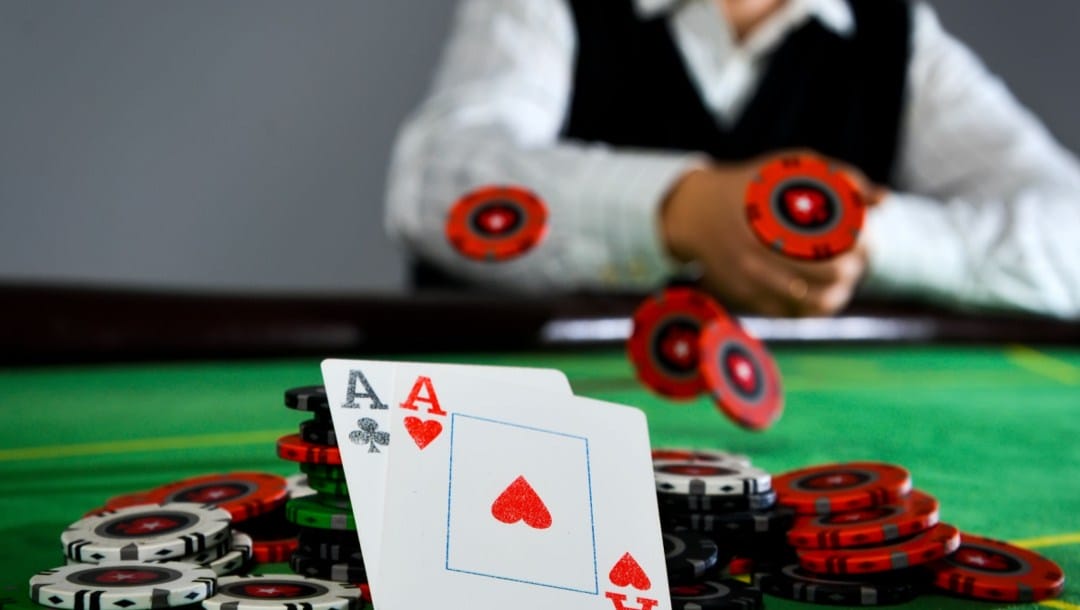 Two ace cards on a pile of poker chips with a player in the background.