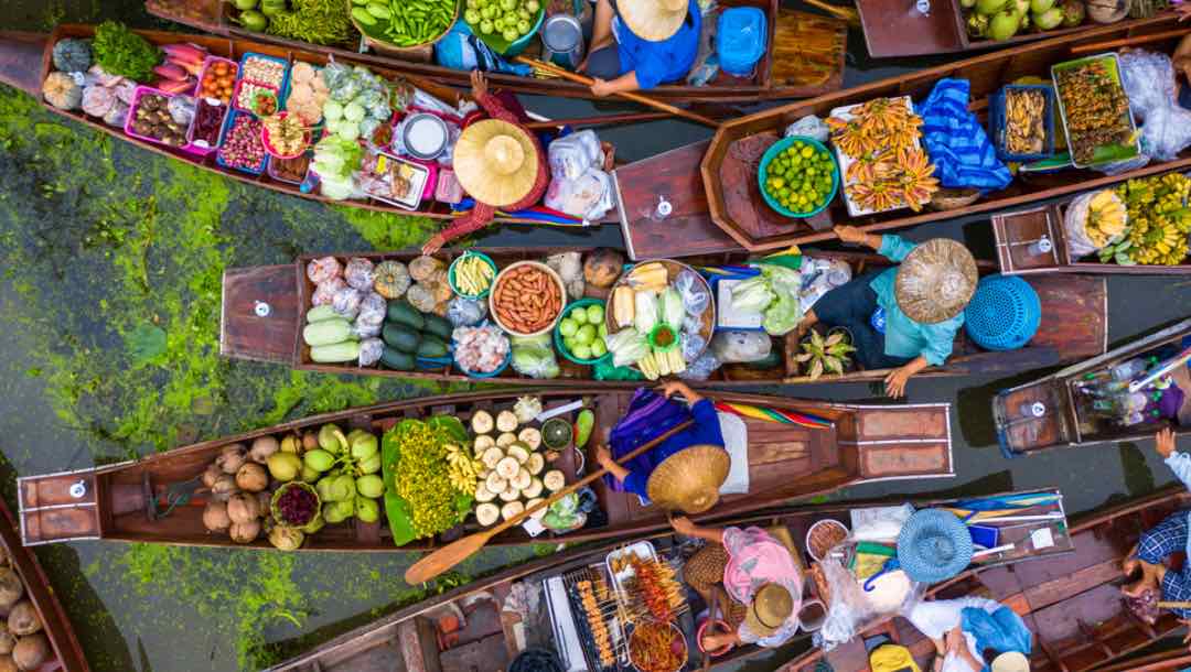 An aerial view of a floating market in Thailand with lots of colorful food on offer.