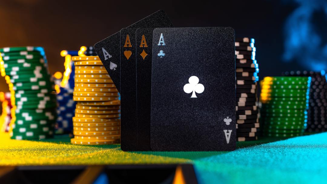 Black ace cards and colorful casino chips on a green felt table.