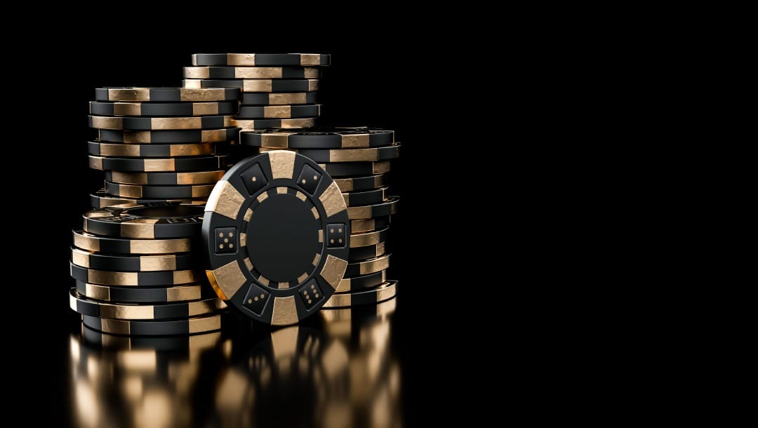 Black and gold casino chips against a black background