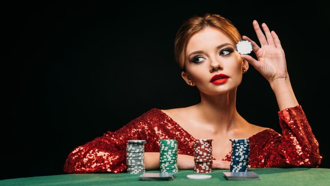 A woman in a red sequined top holding a poker chip.