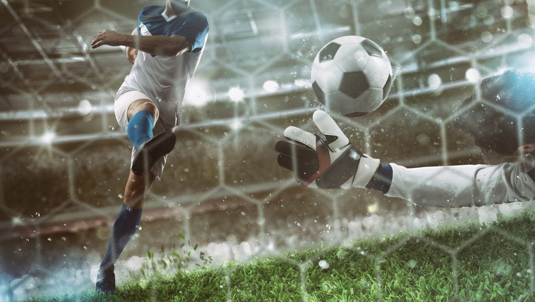 A soccer ball is kicked past a goalie’s outstretched arm.