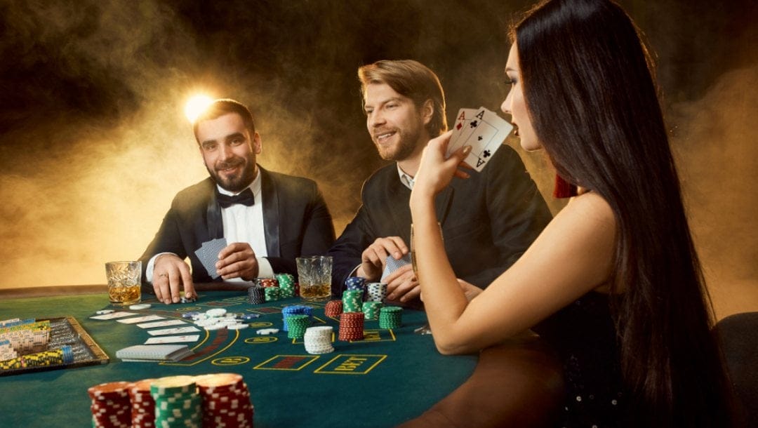 Three people playing poker. The female player shows us her pair of aces.