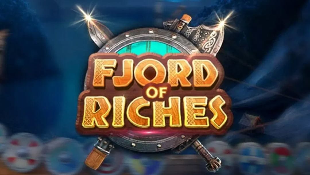 The Fjord of Riches online slot logo is a shade of brown on a wooden board. It contains a metallic shield with swords. The background is dark blue, with various shields at the bottom of the screen.