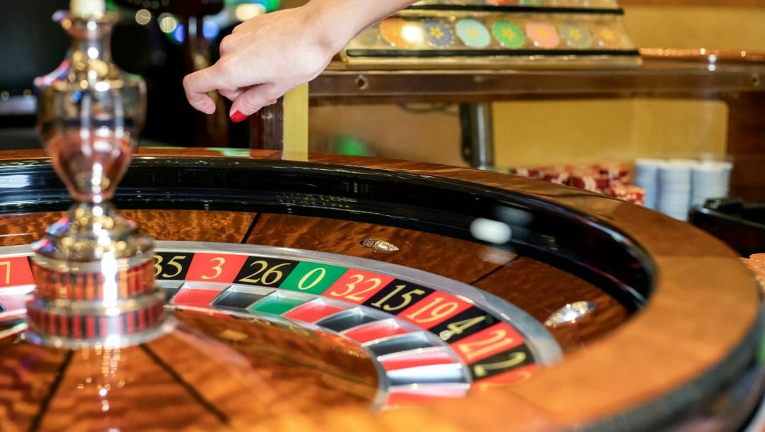 A roulette wheel with the dealer’s hand above it.