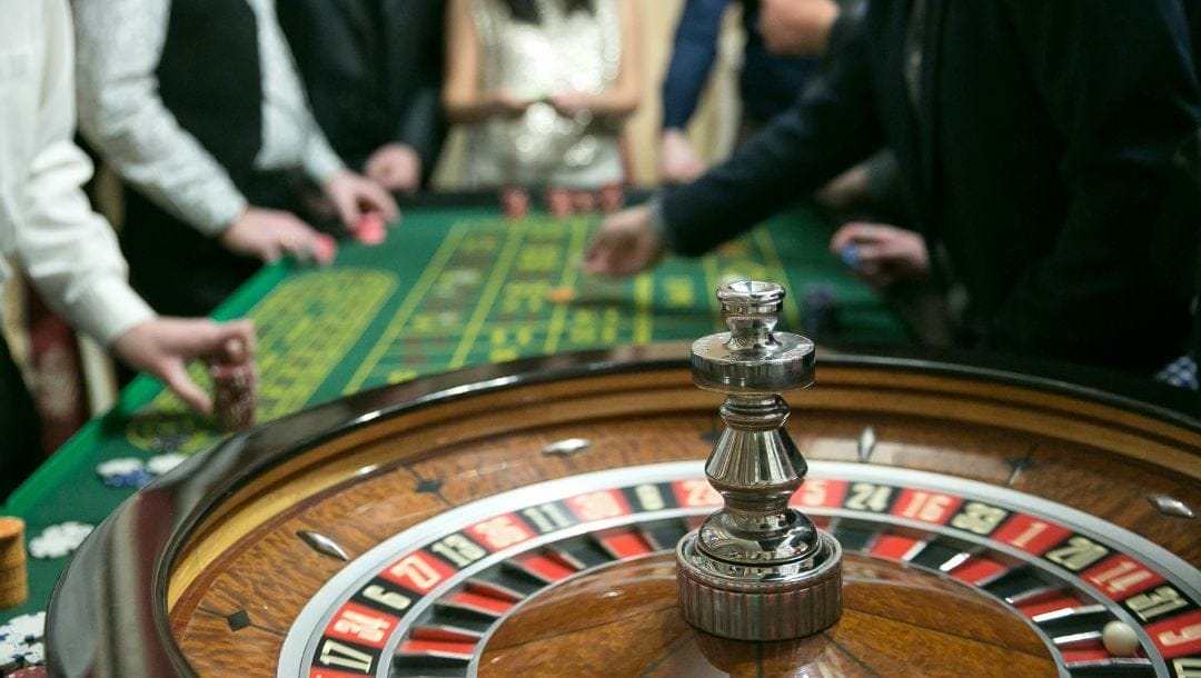 A casino roulette table with people making bets.