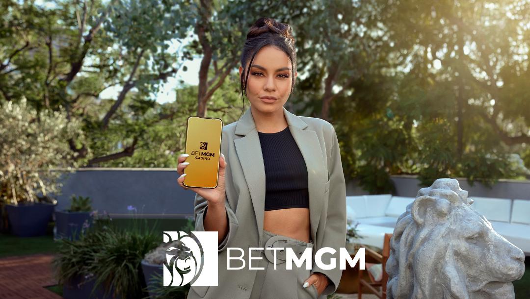 Actress Vanessa Hudgens holding a smartphone with the BetMGM logo on it.