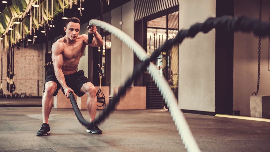 An athlete doing battle ropes in an indoor gym.