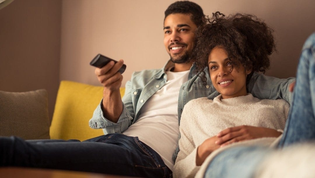 A couple sitting on a couch and relaxing while watching something on TV
