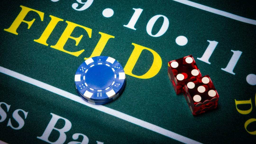 A pair of dice and casino chips on a craps table.