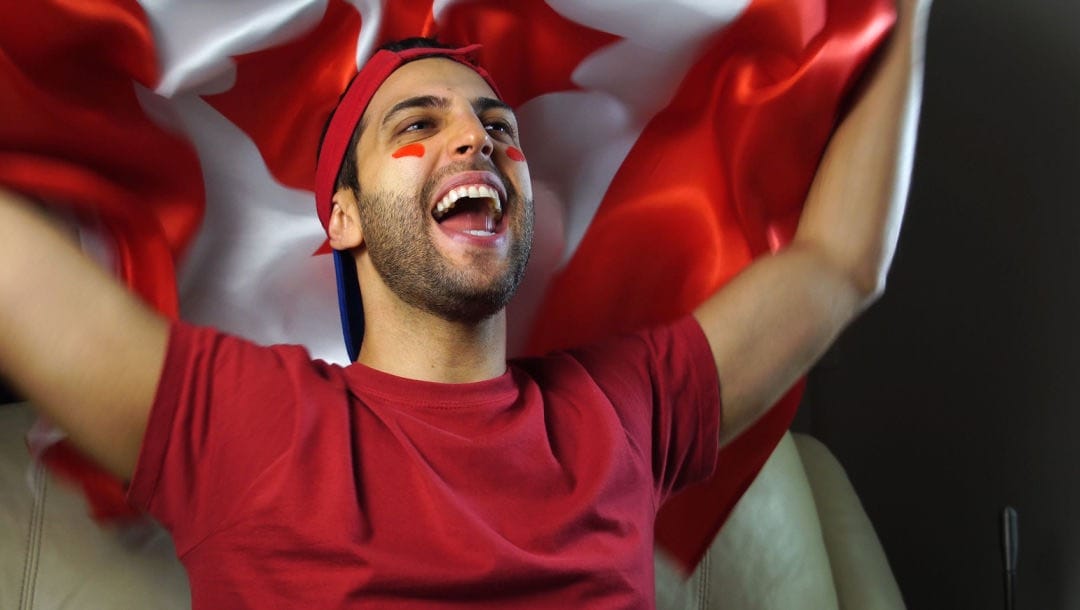 A sports fan holding up a Canadian flag.