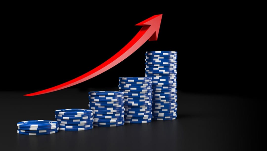 Poker chips stacked in increasingly larger piles with a red arrow following the upward curve.