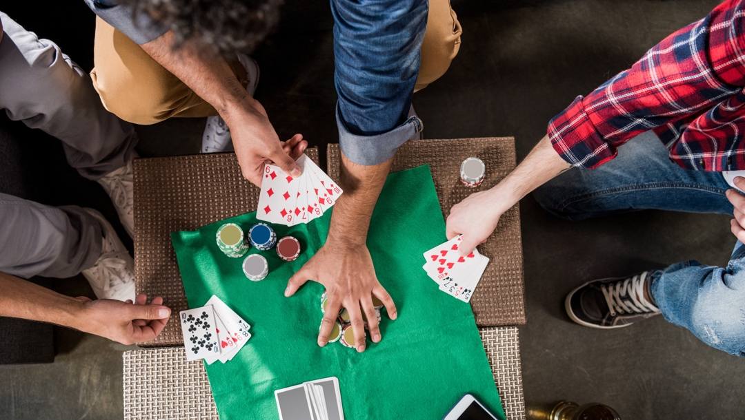 A group of people playing cards on a makeshift table.