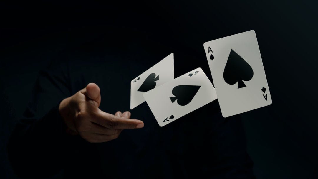 A hand throwing three ace of spades cards.