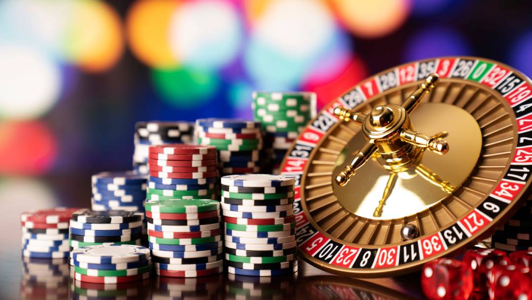 Roulette wheel and casino chips on a reflective surface.