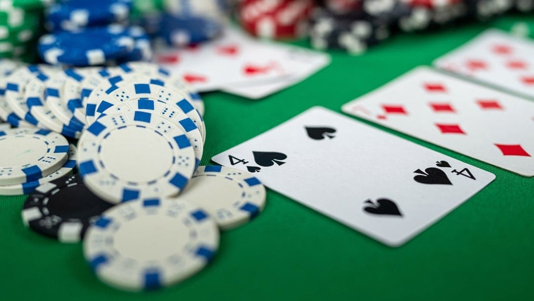 Casino chips and a player’s hand next to three community cards in a game of Texas Hold’em.