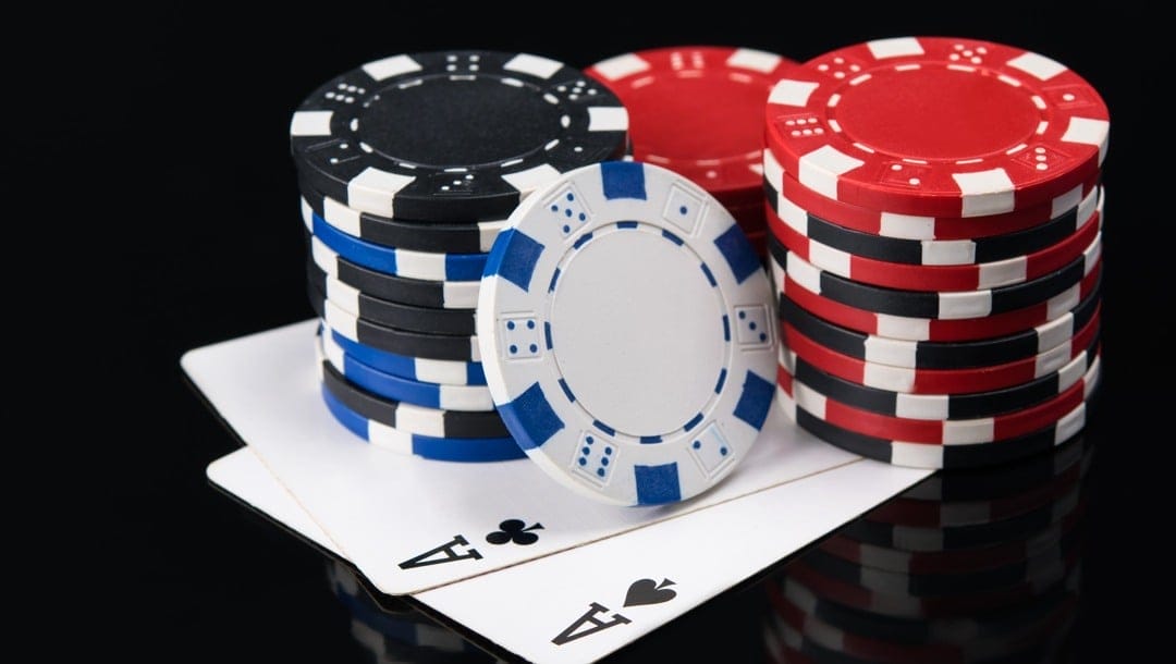 Two aces sitting under a few stacks of poker chips.