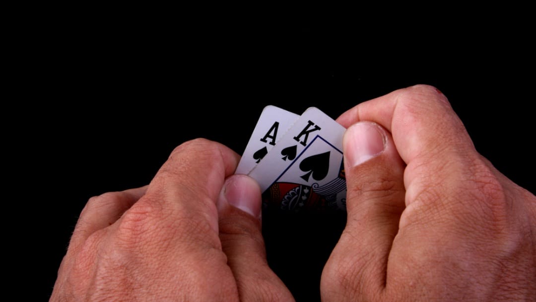 A poker player holding an ace and king of spades in their hand.