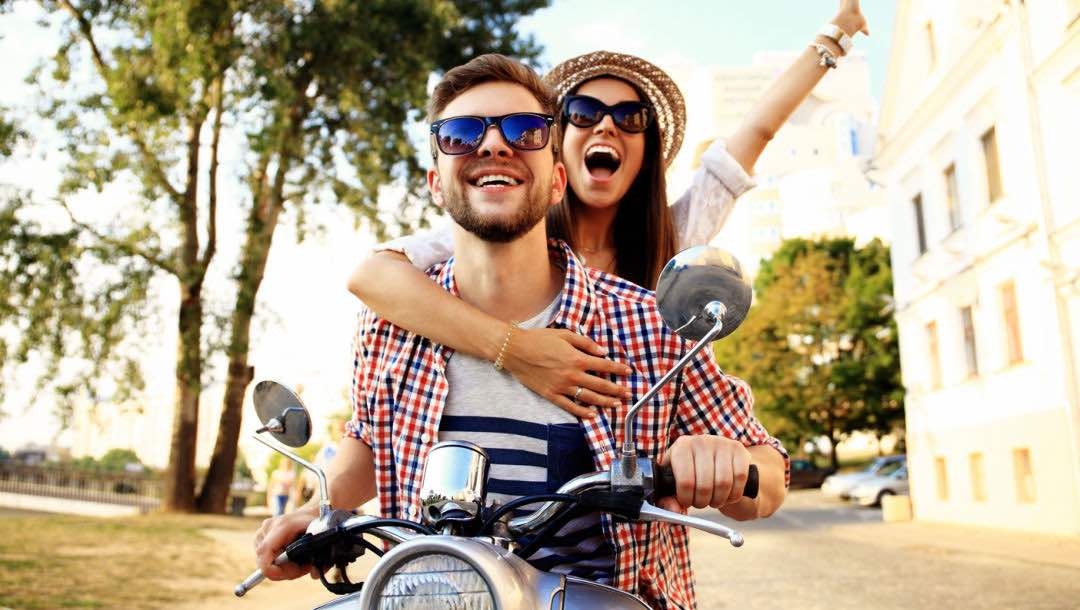 A happy couple touring the city on a motorcycle.