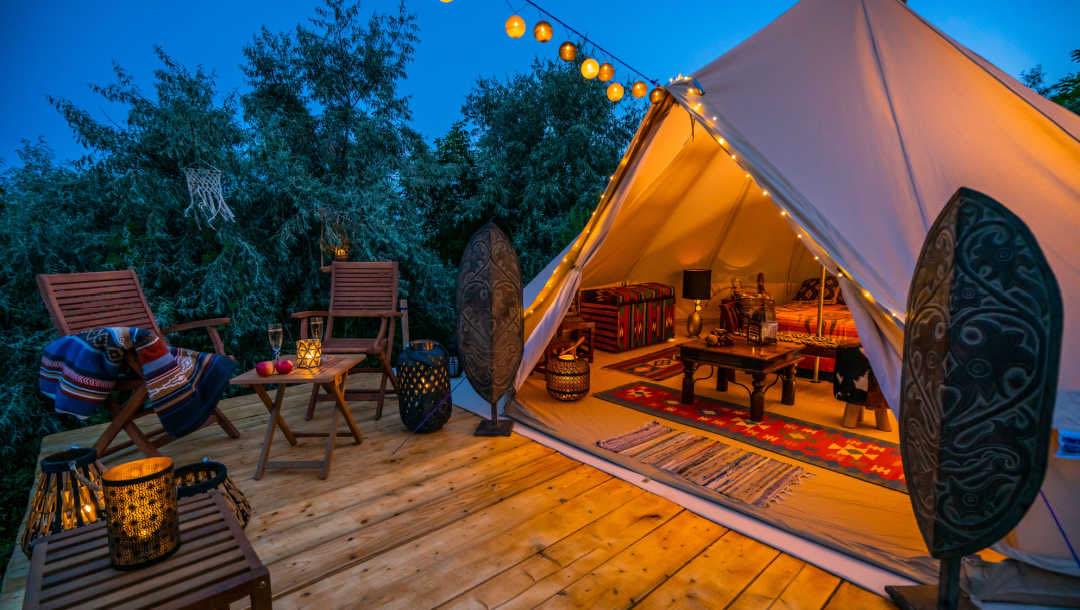 A beautiful teepee with a deck and fairy lights.