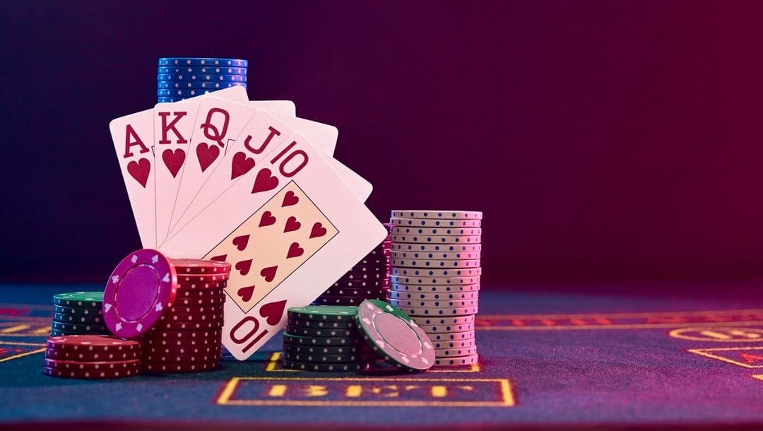 A royal flush propped up by casino chips on a casino game table.