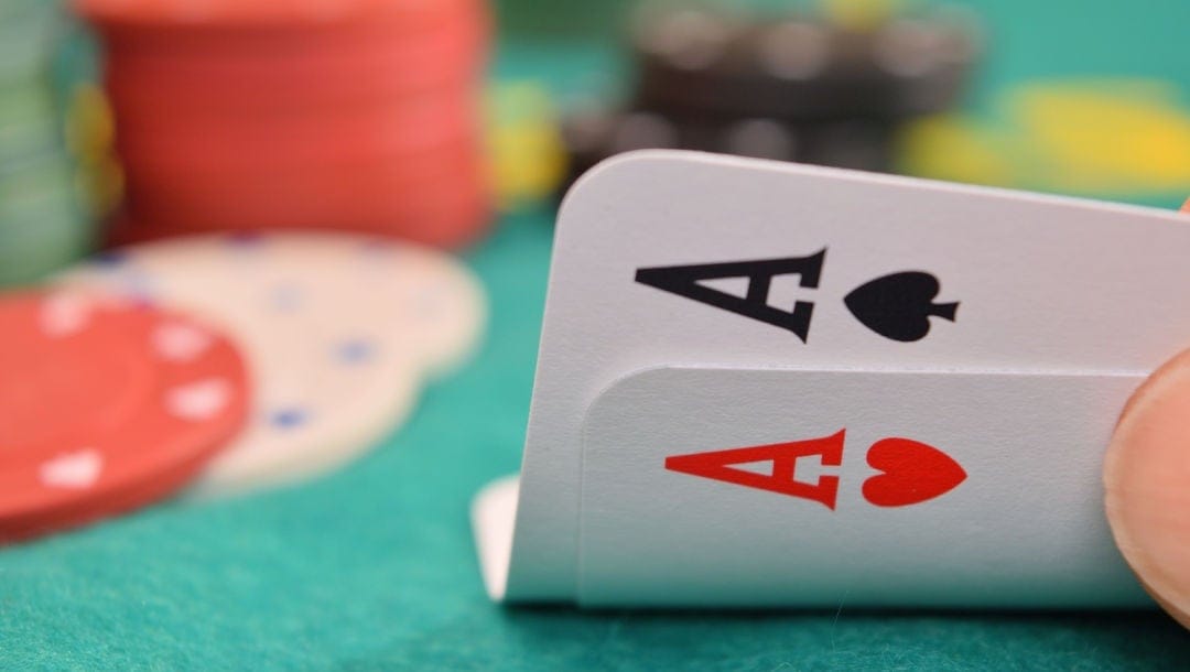 A player lifts up two cards to reveal a pair of aces.