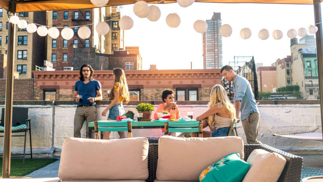 A group of friends gathering around a table at a rooftop bar.