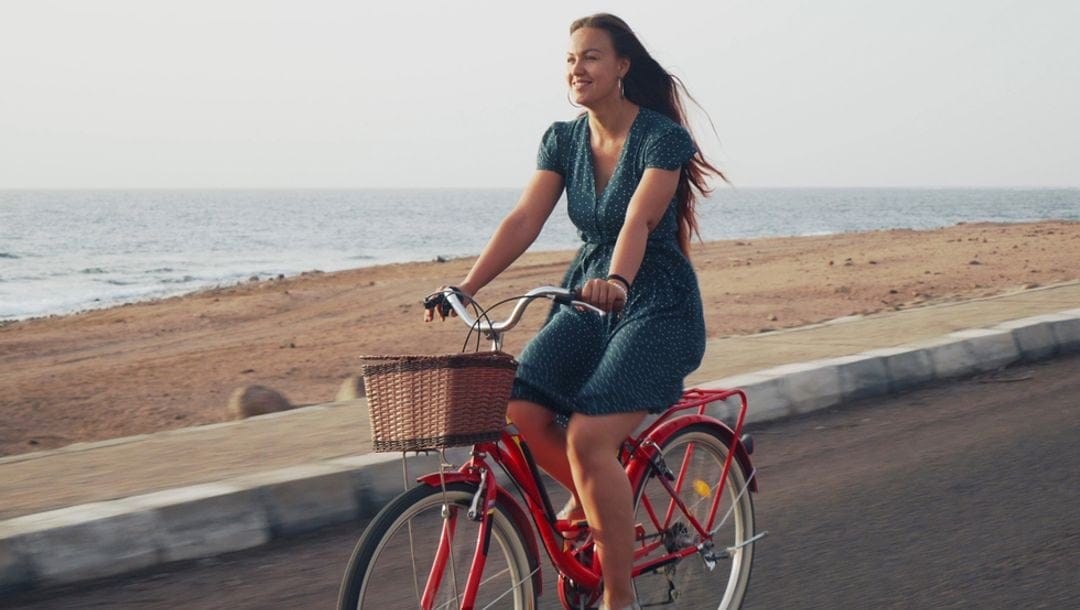 A woman riding a bicycle along the oceanfront.