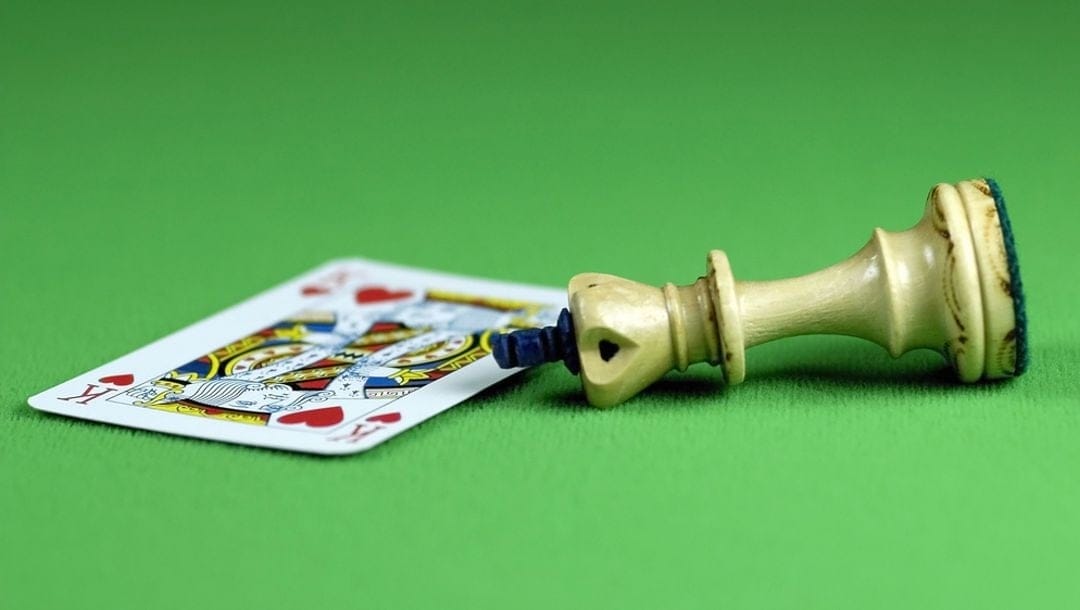 A playing card and chess piece on a green felt table.
