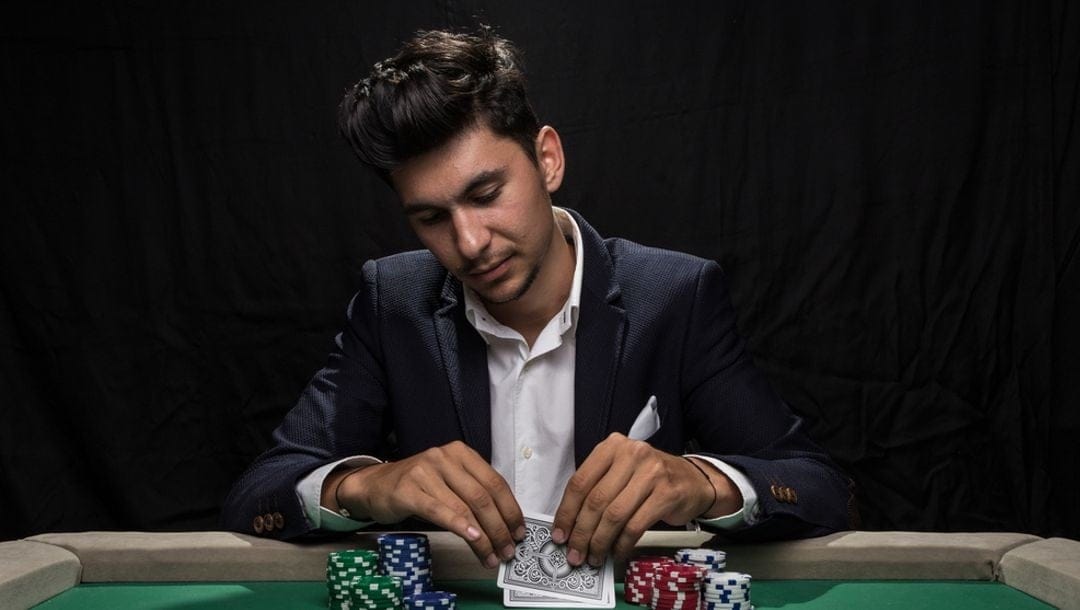 A professional poker player looking at his cards with stacks of chips surrounding them.