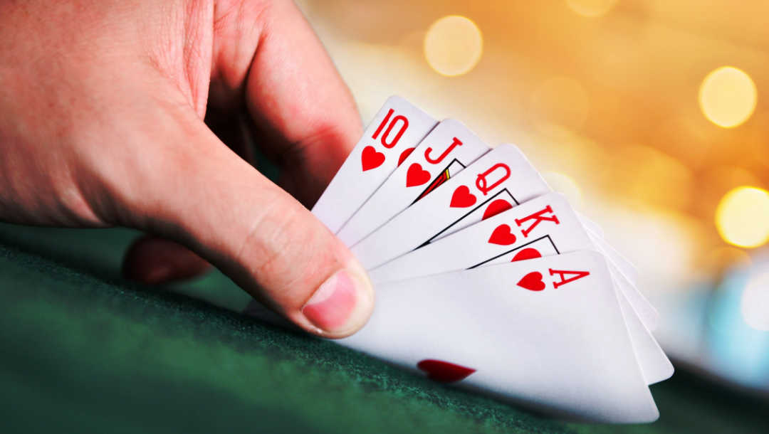 A person looks at a royal flush poker hand.