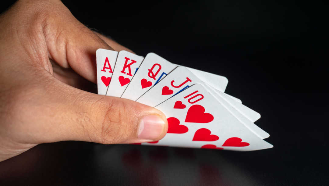 A player looks at a royal flush in their poker hand
