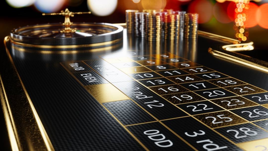 A black and gold roulette table with black and gold casino chips.