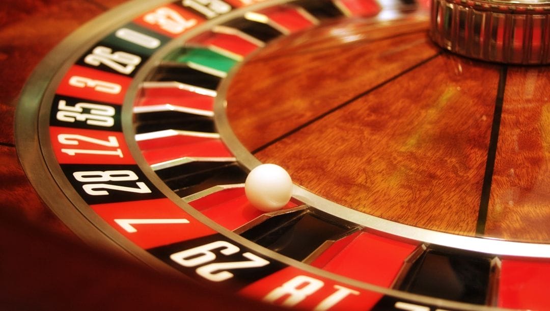 A roulette ball sits in the red 7 pocket of a roulette wheel.